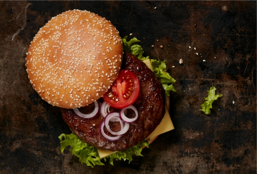 Aufgeklappter Hamburger mit Patty, Tomate und Zwiebeln