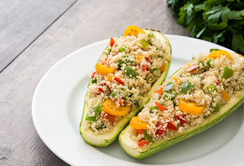 zwei gefüllte Zucchinihälften angerichtet auf einem weißen Teller