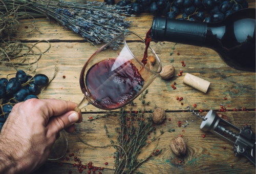 Rotwein wird in ein Weinglas ausgeschenkt