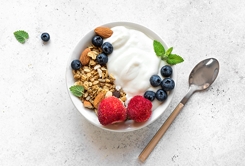 Joghurt in einer Schüssel mit Haferflocken, Mandeln, Blaubeeren, Himbeeren und Erdbeeren
