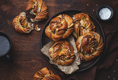 Kanelbullar - Schwedische Zimtschnecken Kanelbullar - Schwedische Zimtschnecken auf einem schwarzen Teller