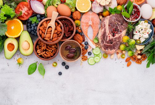 Verschiedenes Obst, Gemüse, Nüsse, Fisch und Fleisch vor weißem Hintergrund