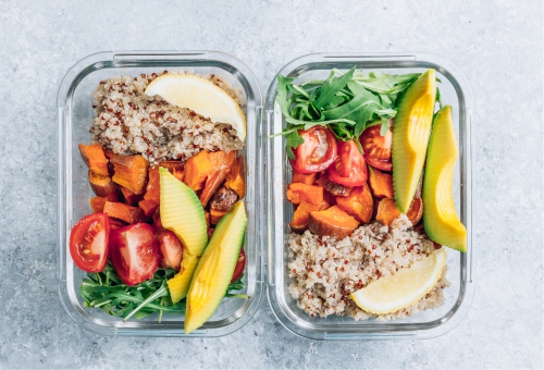 Zwei Glasdosen mit Quinoa, Süßkartoffel, Avocado, Tomaten und Rucola