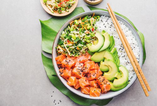 Schüssel mit Lachs, Avocado, Reis und Gurkensalat als Poke-Gericht