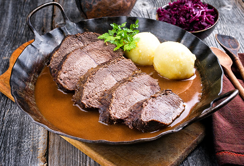 Sauerbraten miot Rotkohl und Klößen auf Teller