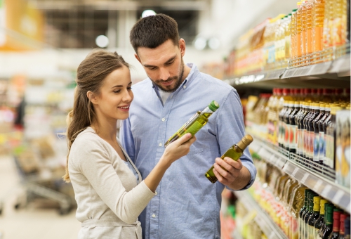 Eine Frau und ein Mann vergleichen in einem Supermarkt Olivenöl-Flaschen