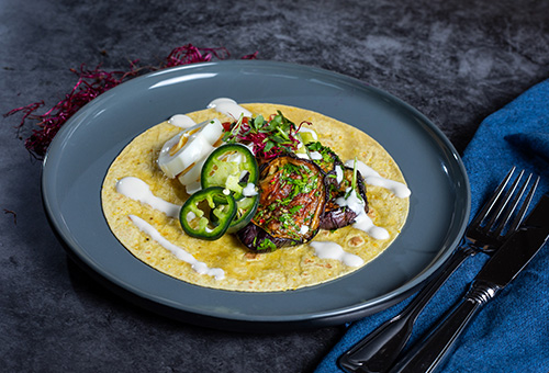 Mais-Tortilla belegt mit gegrillter Aubergine, Jalapenos, hartgekochtem Ei und Tahin-Soße