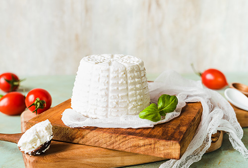 Ricotta auf Holzbrett mit Tomaten angerichtet