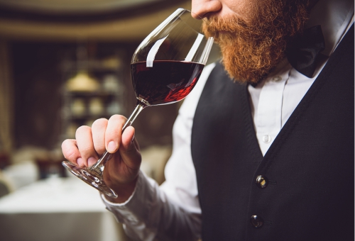 Weinverkostung Mann reicht an einem Glas Rotwein