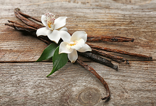 Vanilleschoten und Vanilleblüte auf Holztisch