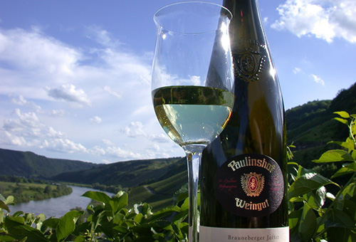 Weinflasche von Weingut Paulinshof mit Weinglas vor Panorama von Weinberg und Mosel