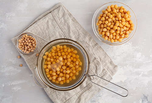 Aquafaba: Kichererbsenwasser Kichererbsen zum Abtropfen in einem Sieb über einer Schüssel mit Aquafaba
