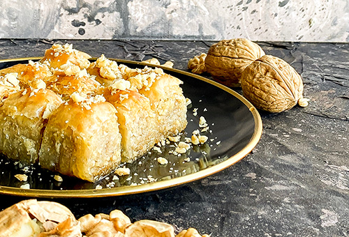 Baklava auf einem Teller und Walnüsse im Hintergrund