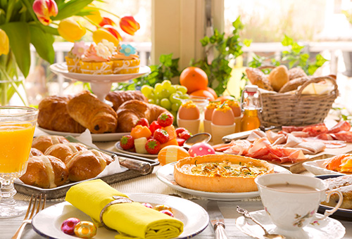 Oster-Brunchbuffet mit Quiche, Hot Cross Buns, Pain au Chocolat, Schinken, Kaffee, hartgekochten Eiern und Cupcakes