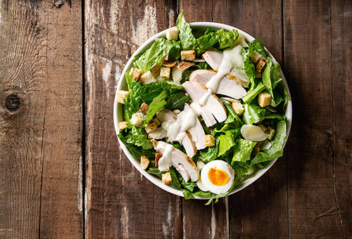 Ceasar Salad mit Romanasalat, Croutons, Hähnchenbrust und Ei von ob fotografiert.