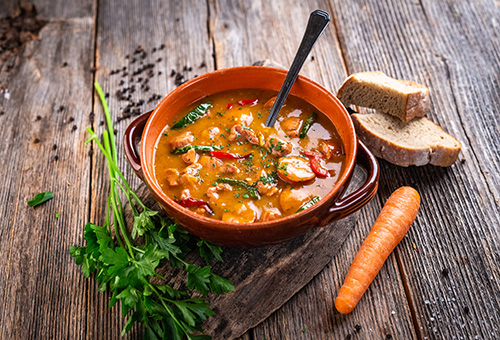 Eintopf mit Paprika, Rindfleisch und Kartoffeln in einer Schüssel mit einem Löffel