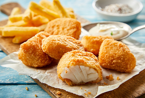 Fish 'n' Chips, frittierter Fisch und Pommes, auf einem Holzbrett angerichtet