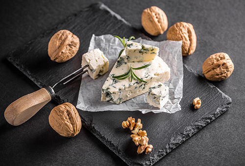 Ein Stück Gorgonzola und Walnüsse auf einer Schieferplatte