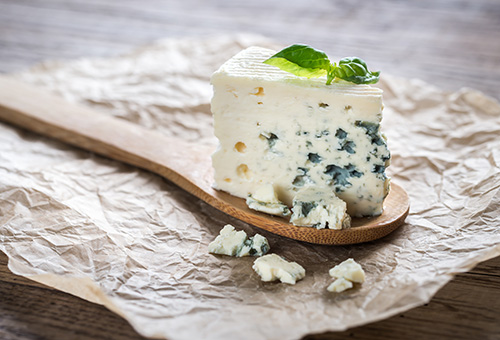 Ein Stück Gorgonzola auf einem Holzlöffel