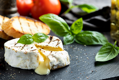 Geschmolzener, angeschnittener Camembert auf Schieferplatte