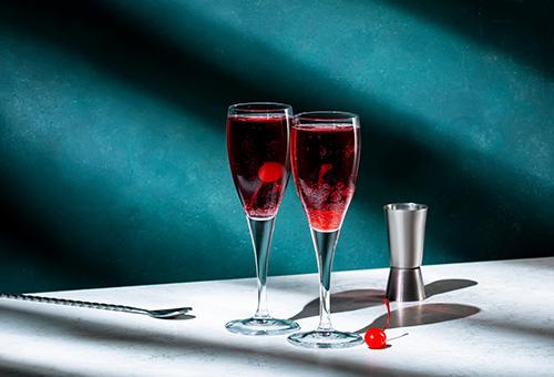 Kir Royal Zwei Gläser mit Kir Royal auf einem Tisch von einer blauen Wand