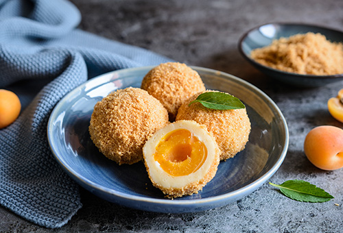 Marillenknödel Drei ganze und ein halber Marillenknödel in einem grauen Teller
