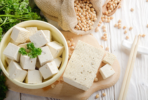 Block Naturtofu auf Schneidebrett und Tofustücke in Schale