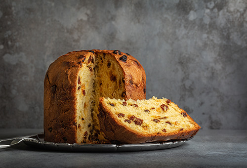 Panettone auf einem silbernen Teller - angeschnitten und Stück liegt davor