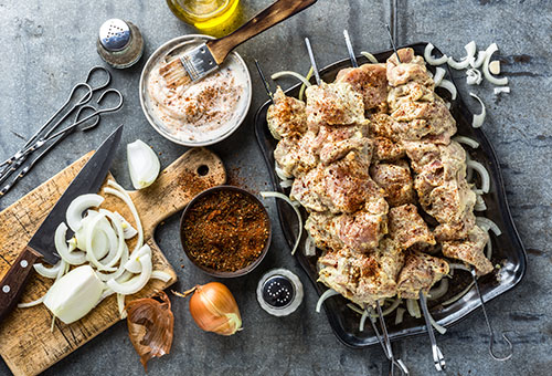 In Joghurt Marinade mariniertes Fleisch auf Schaschlik Spießen auf einem Holzbrett