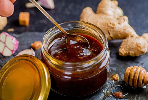 Soja-Marinade in einem offenen Schraubglas mit Ingwer und Knoblauch im Hintergrund