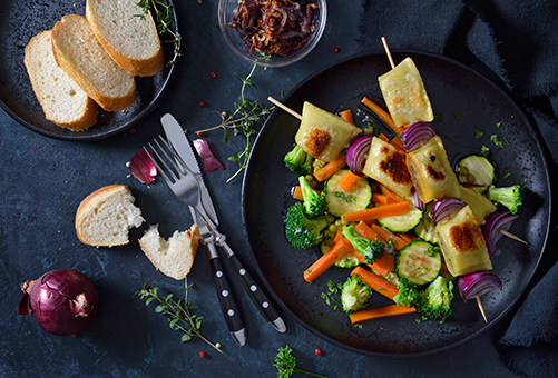 Vegetarische Hausmannskost - Maultaschen Maultaschen auf Spießen angerichtet auf frischem Gemüse in einer Gusspfanne