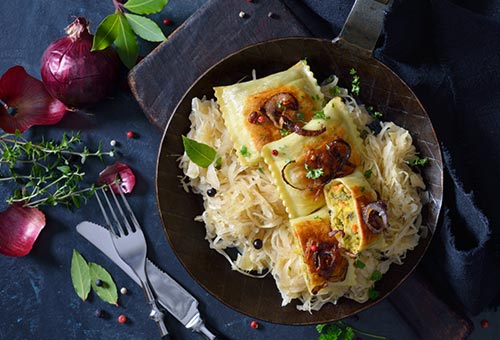 Wissenswertes über Maultaschen angebratene Maultaschen auf Zwiebeln in einer Gusspfanne angerichtet