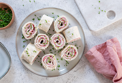 Ameuse Gueule Frischkäse-Putenbrust-Rollen angerichtet auf einem weißen Teller mit einer rosa Serviette