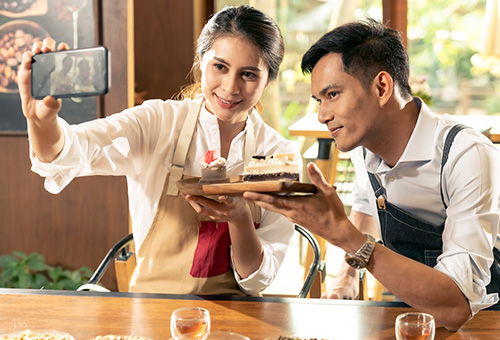Gastronomie Tipps Social Media Zwei Kellner, die ein Bild mit einem Handy als Selfie für Social Media aufnehmen.