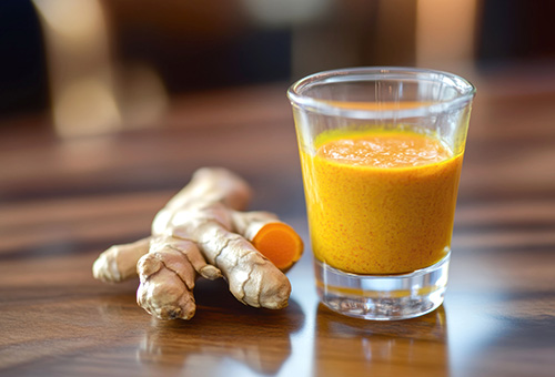 Ingwer und gesundheitliche Wirkung Ingwerknolle und pürierter Ingwer im Glas