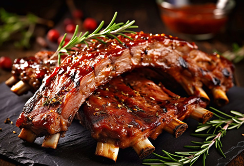 Zwei Spareribs liegen auf einer Schieferplatte mit Rosmarinzweigen