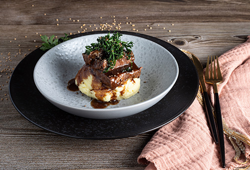 US-Short-Ribs mit Petersilie und Kartoffelbrei auf Teller