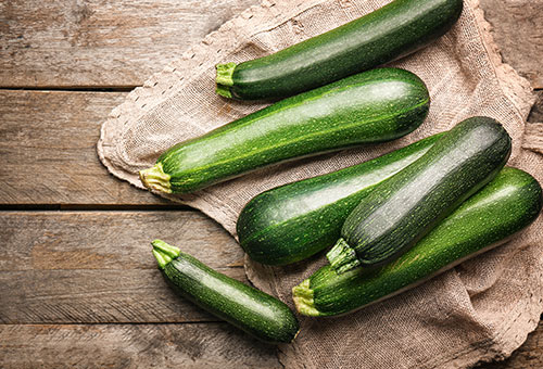 Zucchinigrößen Zucchini in verschiedenen Größen auf einem Leinentuch auf Holzuntergrund